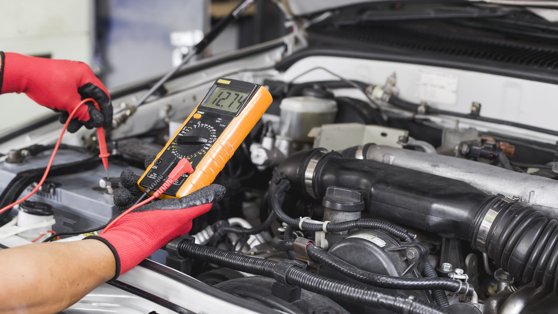 A technician is checking the car battery for availability.