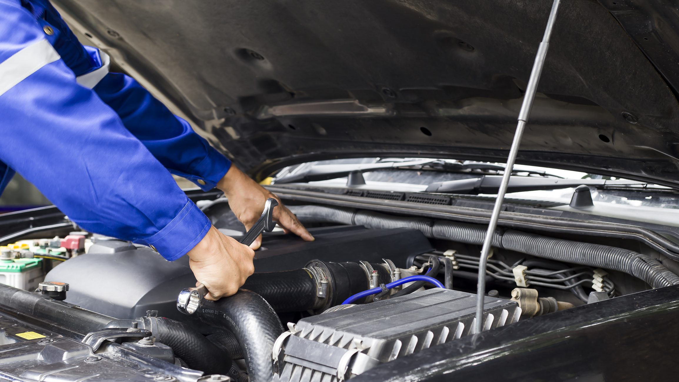Car mechanic working on car engine, car maintenance concept.